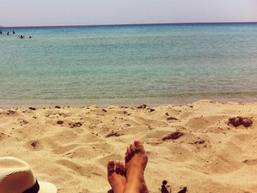 a person laying in the sand on the beach at Goldfish Seaside Luxury Houses in Kómi