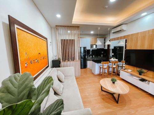 ジャカルタにある2 Bedrooms Permata Hijau Suites Apartmentのリビングルーム(ソファ、テーブル付)、キッチンが備わります。