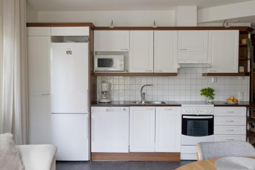 a kitchen with white cabinets and a white refrigerator at Alppitähti, Huoneisto Hilla in Levi