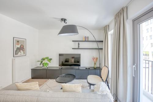 una sala de estar blanca con mesa y sillas en Cosy Seaside Apartments en Ostende
