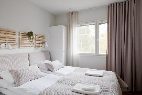 a bedroom with a white bed with two towels on it at Alppitähti, Huoneisto Hilla in Levi