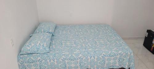 a bed with a blue comforter in a bedroom at Suítes Guriri in Guriri