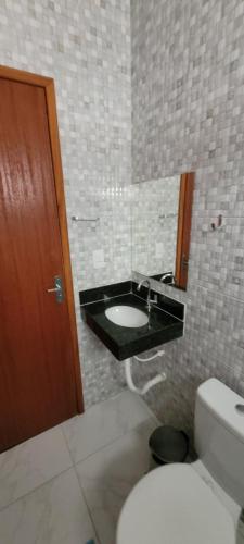 a bathroom with a sink and a toilet and a mirror at Suítes Guriri in Guriri