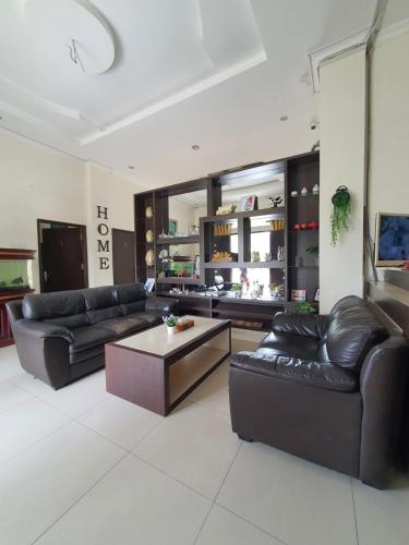 a living room with black leather couches and a coffee table at Mahakam Guest House in Padang