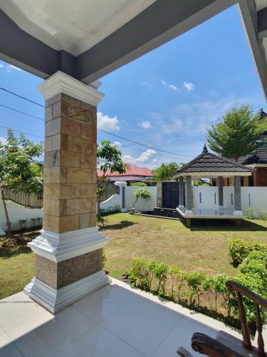 a porch with a brick pillar and a yard at Mahakam Guest House in Padang