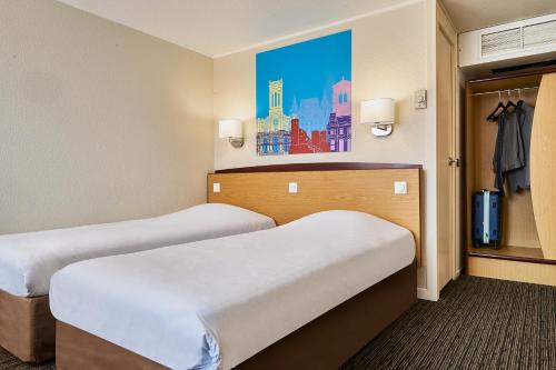 a room with two beds and a painting on the wall at Kyriad Direct Haguenau in Haguenau
