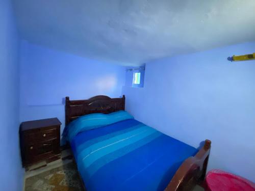 a bed in a room with a blue light at Dar Lazrak in Chefchaouen