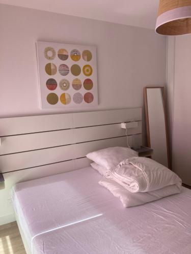 a bed with a white headboard and a pink pillow at Joli appartement coquet et cosy in Royan