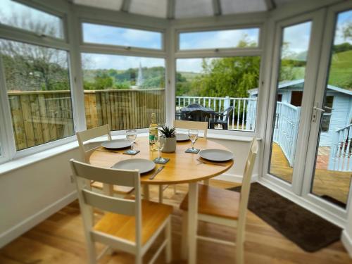 a dining room with a table and chairs and windows at Mary Cottage, Braunton, Devon in Braunton