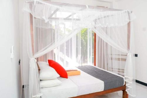 Bett mit Baldachin in einem Zimmer mit Fenster in der Unterkunft Villa Serenity - Jayavikumgama in Weligama