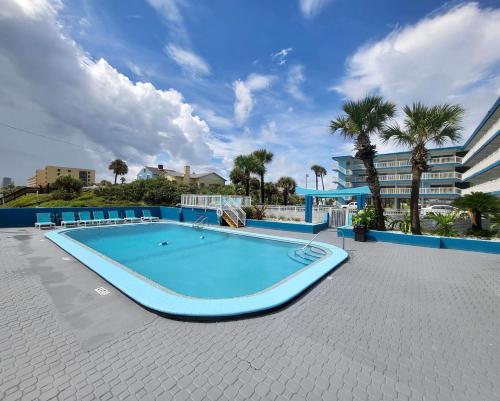 a large swimming pool in a resort with palm trees at Chateau Mar Beach Hotel NEWLY REFURBISHED in Ormond Beach