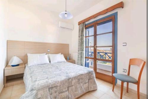 a bedroom with a bed and a window and a chair at Iris - Διαμέρισμα σε πολυκατοικία ως ολόκληρος χώρος in Souvala