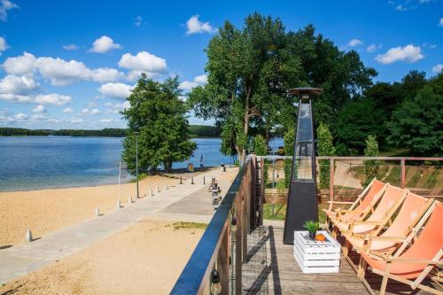 a dock with chairs and a beach and water at Apartament UKIEL PARK 30 przy Plaży Miejskiej - klimatyzacja,free parking,FV in Olsztyn