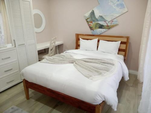 a bedroom with a bed with white sheets at JemmRose Suites in Choc