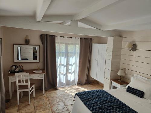 a bedroom with a bed and a desk with a mirror at Le Chant du Coeur in Roussillon