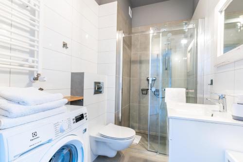 eine Waschmaschine im Bad mit einem Waschbecken und einer Dusche in der Unterkunft LIKE LAKES Ukiel Park 30 - Free parking FV in Olsztyn