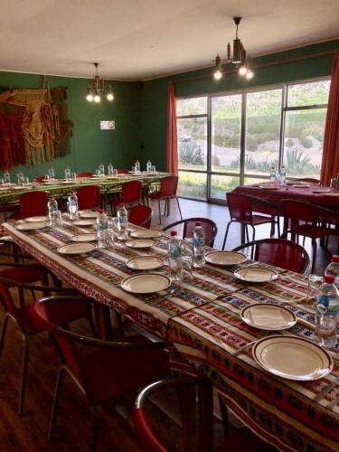 a dining room with a long table with plates and chairs at Hotel Las Vicuñas in Putre