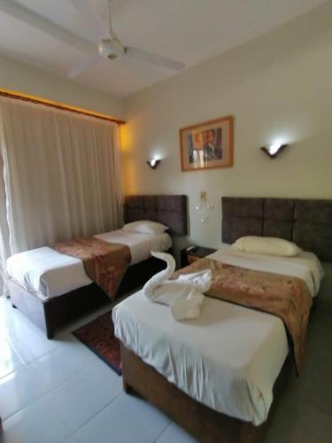 a hotel room with three beds in a room at Rezeiky Hotel & Camp in Luxor