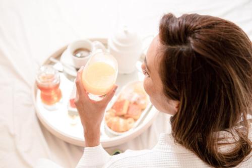 a woman holding up a cup in front of a plate of food at Grande Hotel Termas de Araxá in Araxá
