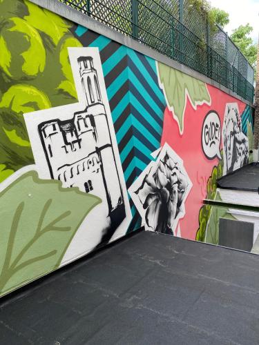 a wall covered in graffiti with a mural of a building at Hotel Rose in Rüdesheim am Rhein