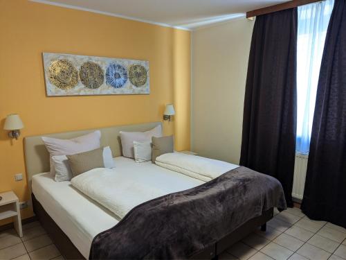 a bedroom with a large white bed in front of a window at Hotel Rath in Schwalmtal