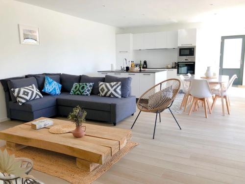 a living room with a blue couch and a table at Maison neuve 4 étoiles plain-pied proche de la mer in Plurien