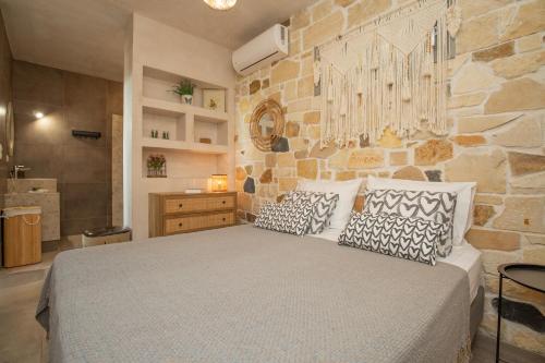 1 dormitorio con 1 cama grande y pared de piedra en Markos Home, en Koutsounari