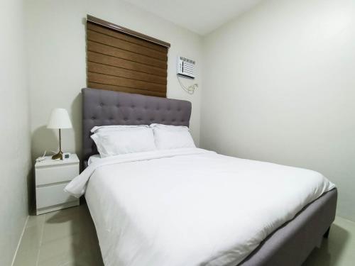 a bedroom with a large white bed with a wooden headboard at Manzil Anilao B&B in Mabini