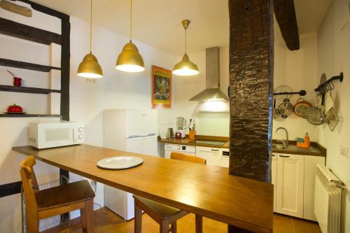 uma cozinha com uma mesa de madeira com cadeiras e um micro-ondas em Casa junto a Reserva del Saja, bosque y montaña em Arenas de Iguña