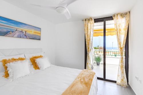 a bedroom with a white bed and a large window at BuenaVista Sunflower Apartment in Playa La Arena in Puerto de Santiago