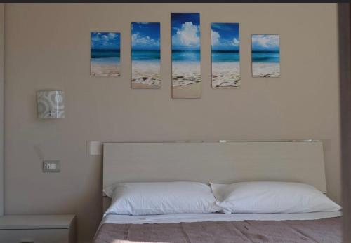 カタンツァーロ・リドにあるLvresidence Roccellettaのベッドルーム1室(壁に4つの絵画が飾られたベッド1台付)