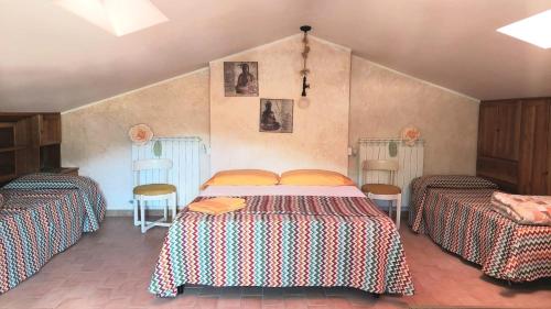 a bedroom with two beds and two chairs at Casa Bannella in Colle della Sponga