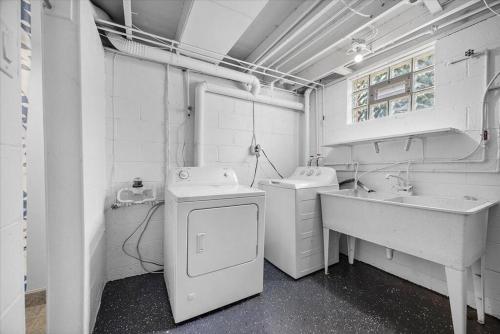La salle de bains est pourvue de 2 lavabos et d'un lave-linge. dans l'établissement Stylish and Bright 4 Bedroom Home, Amazing Yard with Firepit, Game Room, à Pittsburgh