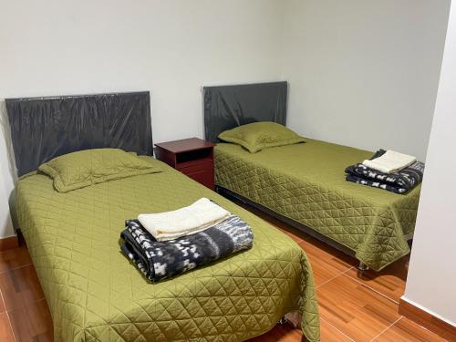 two beds in a room with green sheets and pillows at Apart La Merced in Caraz