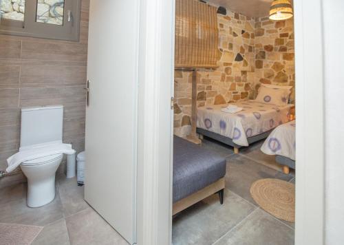 a bathroom with a toilet and a bedroom with two beds at Markos Home in Koutsounari