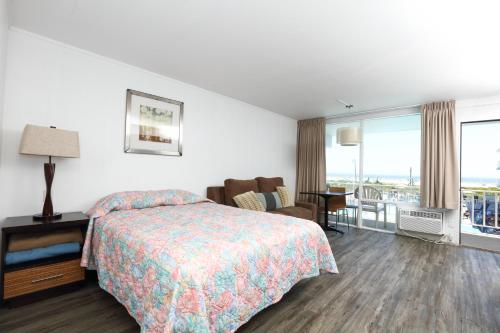 a hotel room with a bed and a chair and a table at Olympic Island Beach Resort in Wildwood Crest