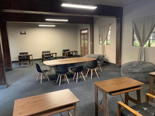 a room with wooden tables and chairs and windows at FRONTERA 49 Roma Norte Hostal in Mexico City