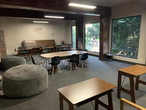 a large room with tables and chairs and windows at FRONTERA 49 Roma Norte Hostal in Mexico City