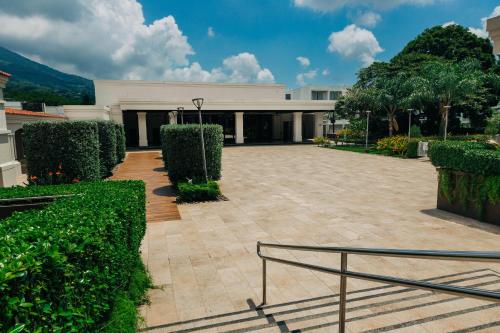 a large white building with bushes in front of it at Plaza Hotel and Suites in San Salvador