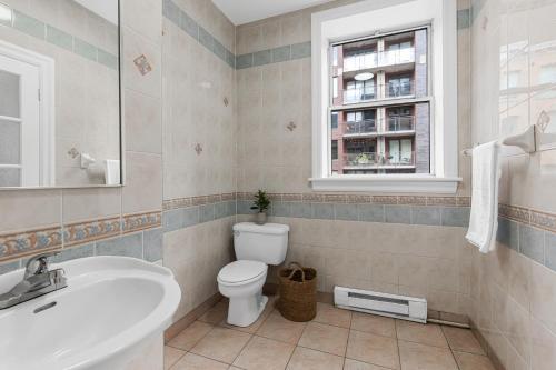 a bathroom with a toilet and a sink and a window at Le Sand & Stone Hotel in Montréal