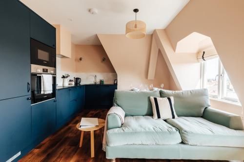 a living room with a blue couch and a kitchen at Redland Suites - Apartment 7 in Bristol