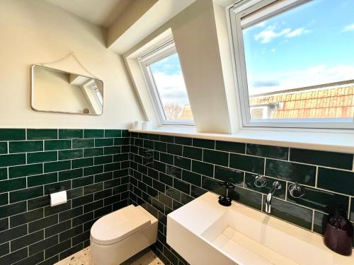a bathroom with a toilet and a sink and two windows at Redland Suites - Apartment 7 in Bristol