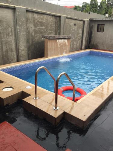 a pool with a wooden deck and a swimming pool with a water fountain at Alluring View Hotel - Allen Avenue in Lagos