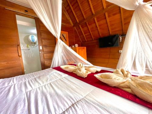 a bed with white sheets and towels on it at Ayu Laba Beach Villa and Resto in Nusa Penida