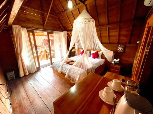 a bedroom with a bed with a mosquito net at Ayu Laba Beach Villa and Resto in Nusa Penida