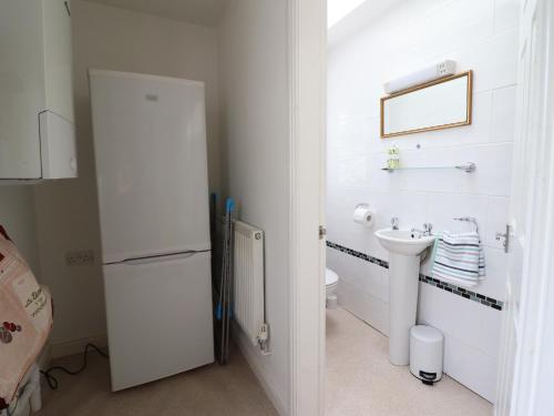 a white bathroom with a sink and a refrigerator at 24 Cadnant Park in Conwy