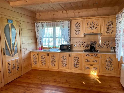 una cocina con armarios de madera y una ventana en Domek u Orszulaków en Witów