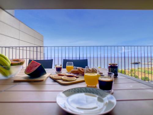a table with plates of food and glasses of orange juice at The Best Sea View Apartment by LovelyStay in Funchal