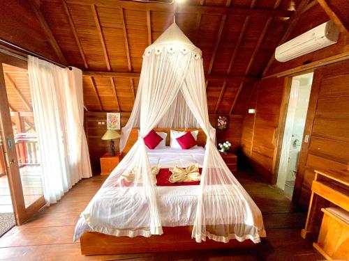 a bedroom with a bed with a mosquito net at Ayu Laba Beach Villa and Resto in Nusa Penida