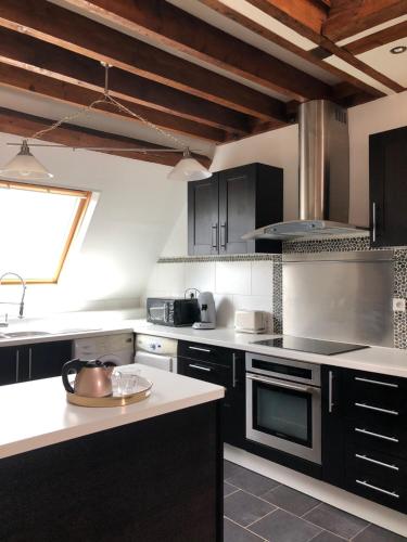 une cuisine avec des armoires noires et des comptoirs blancs dans l'établissement L'Appart'Mans, luxueux, spacieux, bien situé, au Mans